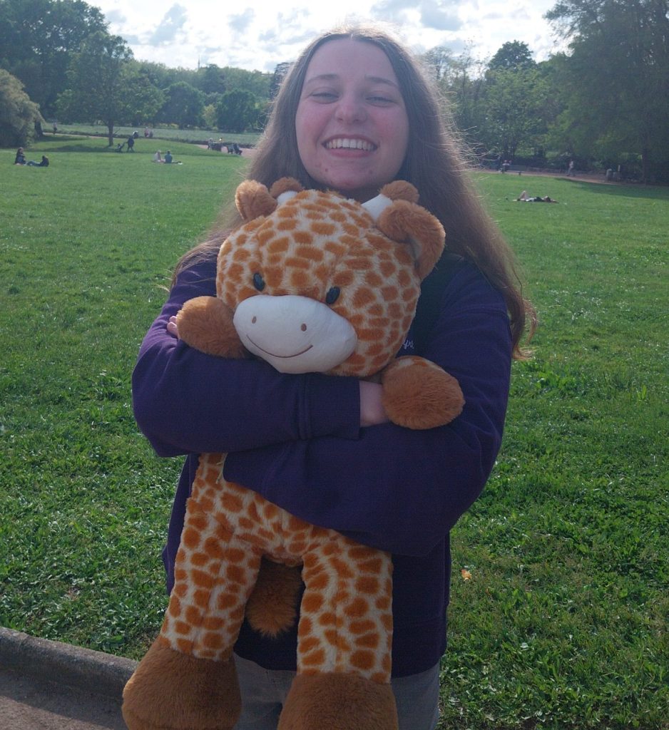 Maréva sourire au lèvres avec une girafe dans les bras